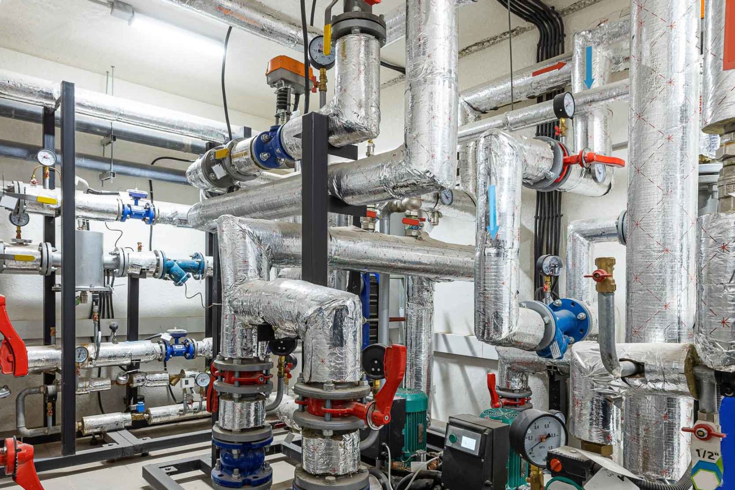 Industrial basement with heating pipes, pressure gauges, valves and heat exchangers.